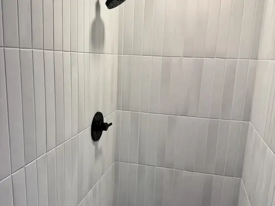 Finished tiled shower with matte black shower head and valve trim